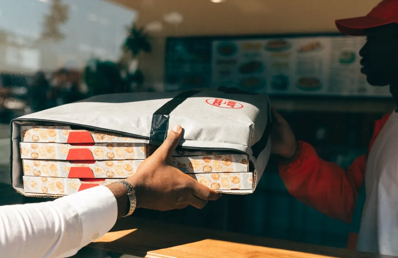 Hands folding a pizza box on a floured prep table